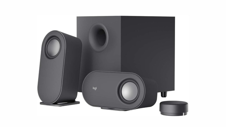 Two black cylindrical speakers with a round, disc-shaped remote and a larger square shaped subwoofer.