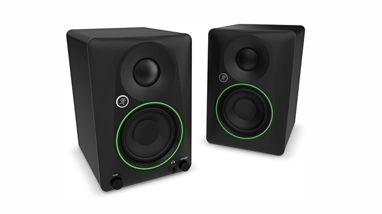 Two boxy speakers in black. one of them has two knobs and a port on it. Both of them have a bright green ring on them with the company's icon.