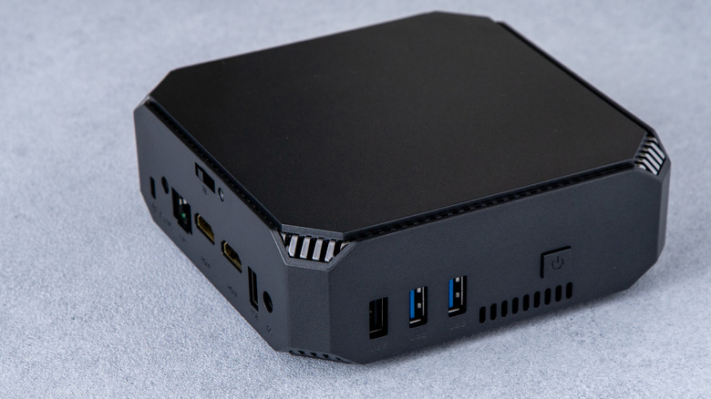 A mini PC with multiple visible ports against a grey surface.