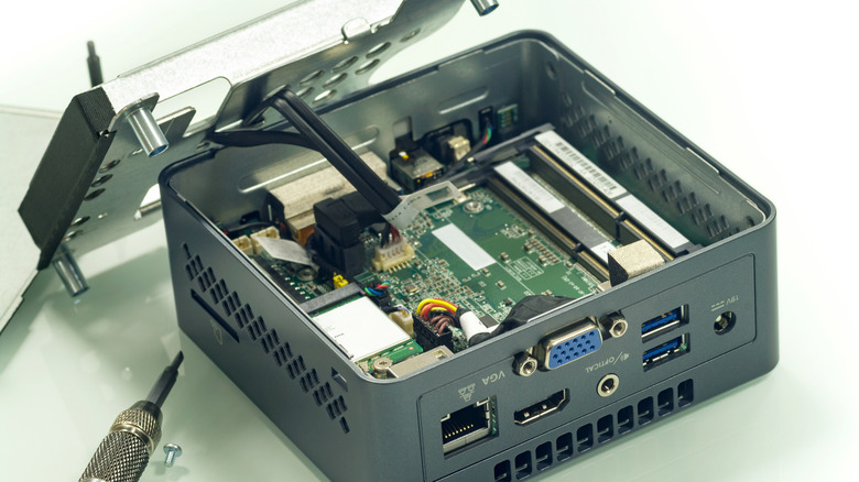 A mini PC with its cover open and a soldering iron nearby.