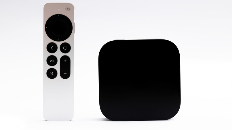 An Apple TV box with its remote against a white background.