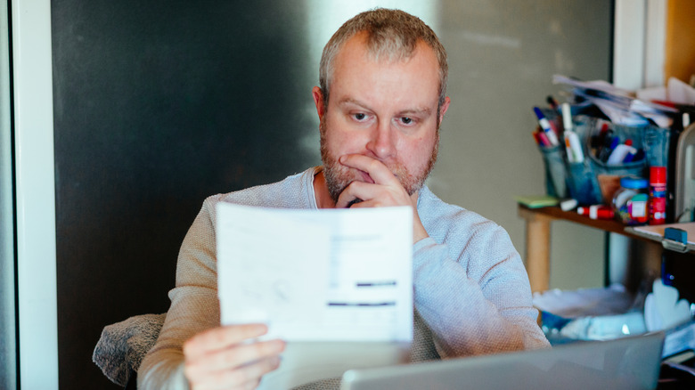 A man looks with concern at his bills.