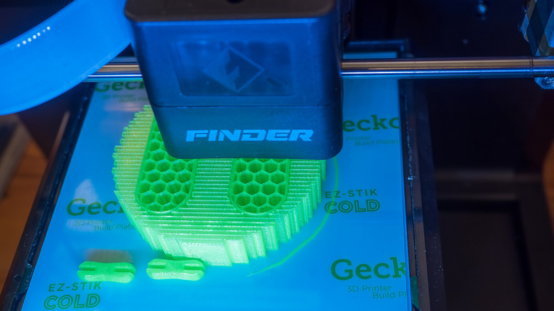 A Flashforge 3D printer in action printing something in luminscent green.