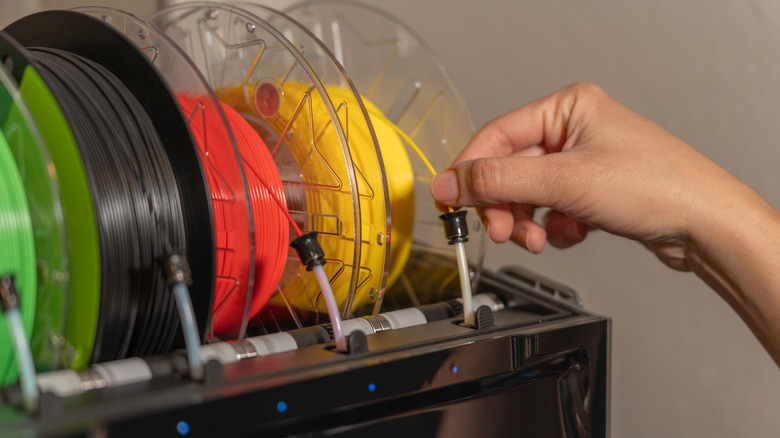 A person adjusting the filament feed on a multicolor 3D printer.