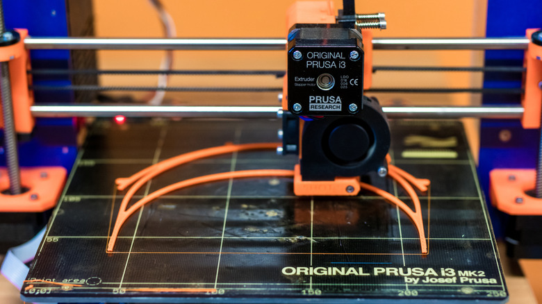 A Prusa i3 MK2 printing an object in orange filament.