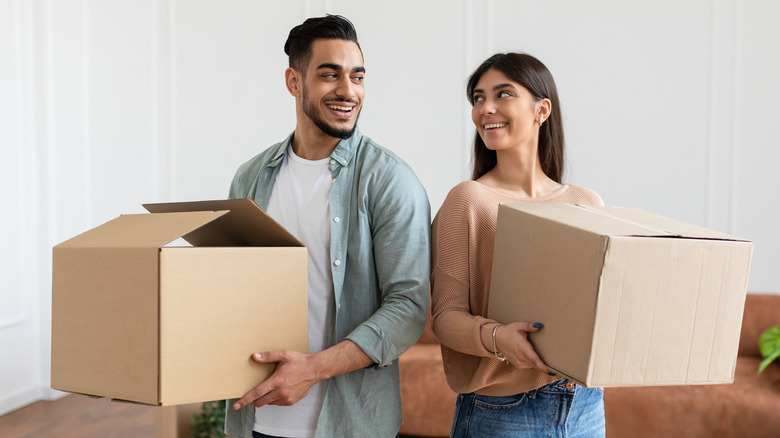 A man and a woman holding cardboard boxes and smiling
