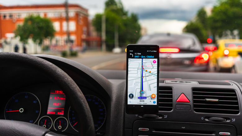 The user interface of Waze, shown on a phone attached to a car's dashboard.