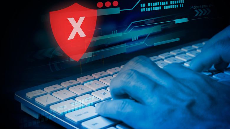 Hands typing on a keyboard with a large red symbol indicating access has been denied.