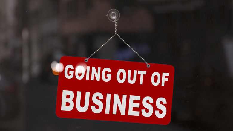 A going out of business sign inside a glass door.