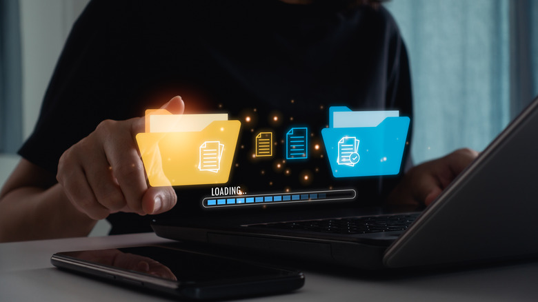 A graphic symbolic of online file syncing floats above a laptop.