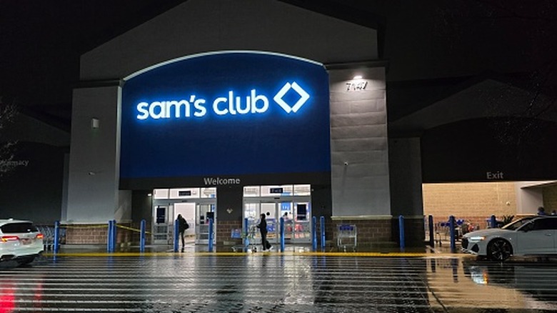 The facade of a Sam's Club store at night, with the logo lit up.