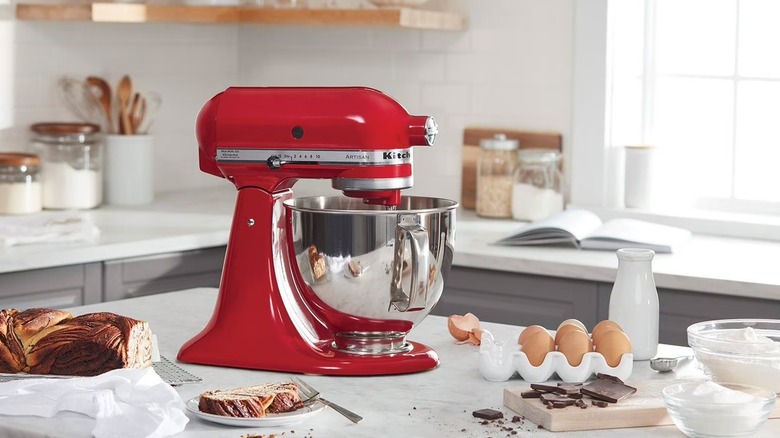 The KitchenAid Artisan Series stand mixer on a kitchen countertop, surrounded by ingredients.