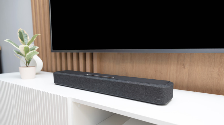 A modern entertainment console with a soundbar on top of it and a wall-mounted TV above it.