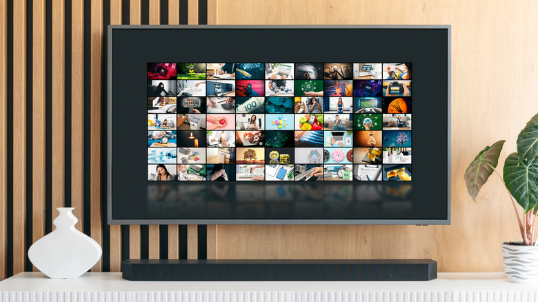 A soundbar sitting on top a of an entertainment center with a TV mounted to the wall behind it.