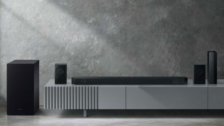 The Samsung HW-Q65C soundbar bundle with satellite speakers and subwoofer sitting on top of an entertainment table.