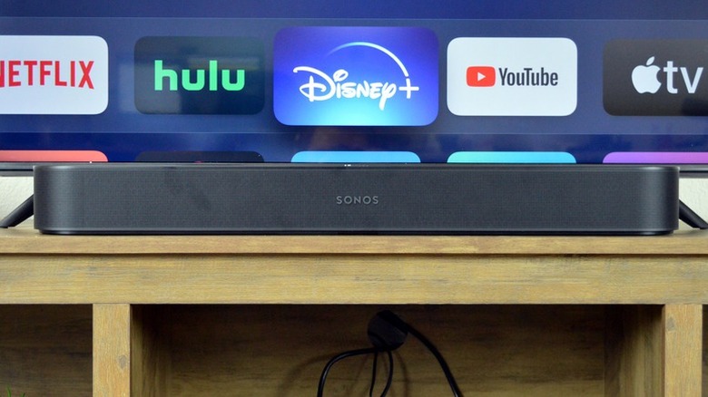 The Sonos Beam Gen 2 in front of a smart TV with streaming apps on the screen.