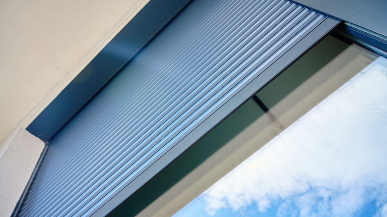 A window with blinds, half-open during the day