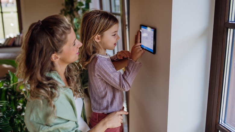 Kid adjusting temperature on the smart thermostat