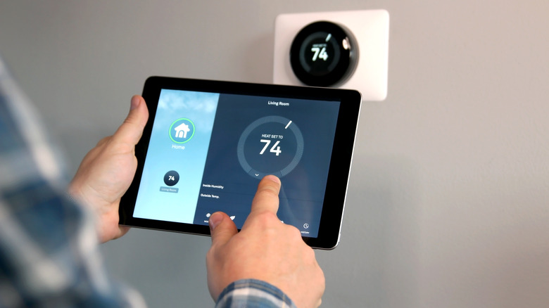 A person changing the temperature of the smart thermostat using a tablet