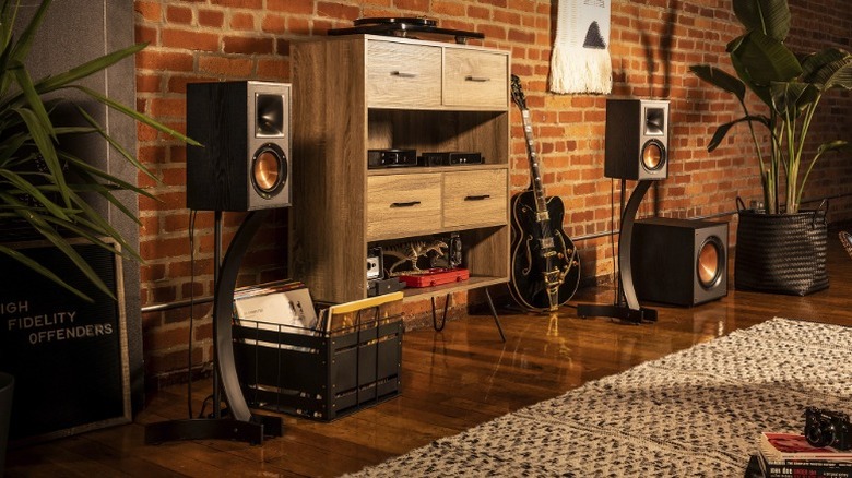 Klipsch R-100SW placed in a vintage-looking room with other audio devices.