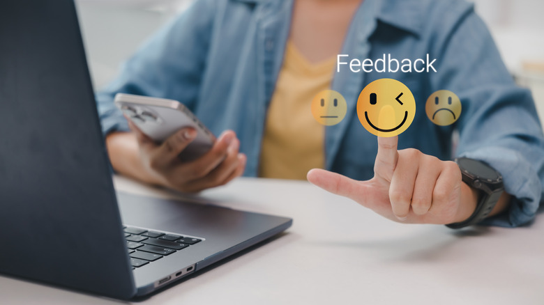 Holographic image of feedback emojis, along with a laptop on the table.