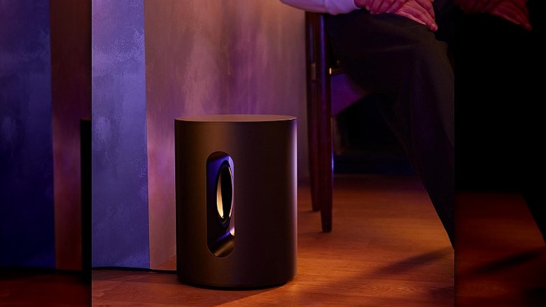 Sonos Sub Mini placed on floor in a dimly-lit room.