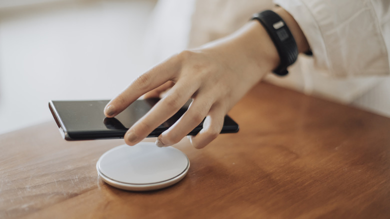A person placing their phone on a wireless charger.