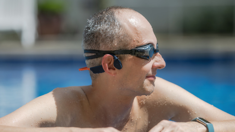 A man wearing bone conduction headphones while in a swimming pool.