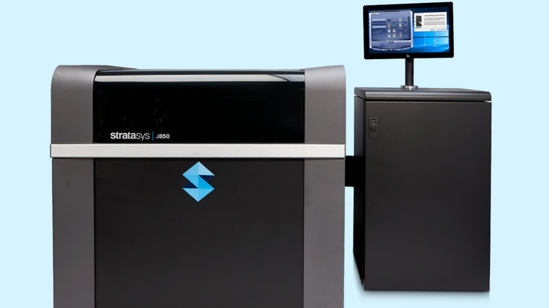 Large Stratasys J850 industrial 3D printer with a separate control unit and touchscreen display on a light background.
