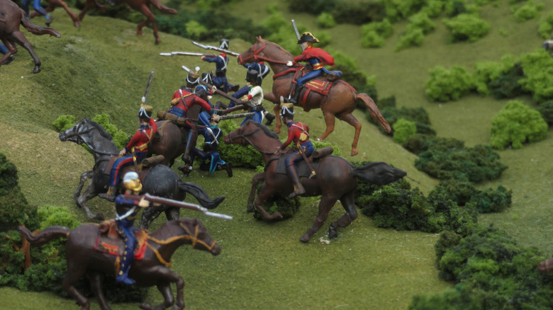 Miniature diorama of a cavalry battle, with painted toy soldiers on horseback fighting on a grassy terrain.