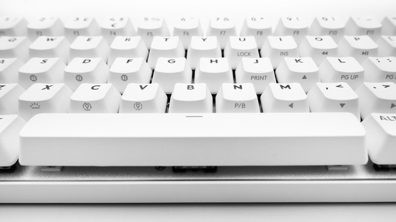 A close-up view of a white mechanical keyboard, focusing on the spacebar and surrounding keys with gray and black lettering.