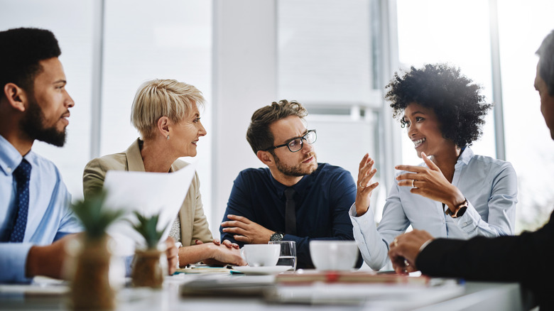 A group of people in business attire gathered around a conference table.