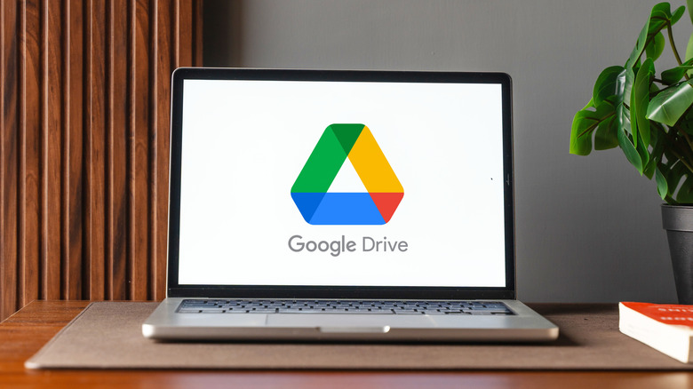 A laptop displaying the Google Drive logo on its screen, placed on a desk in a home or office setting.
