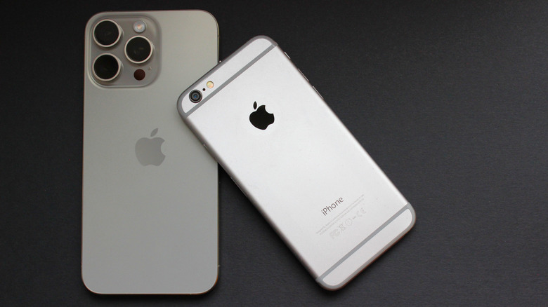 An Apple iPhone 6 on top of an iPhone 15 Pro, both on a black surface.