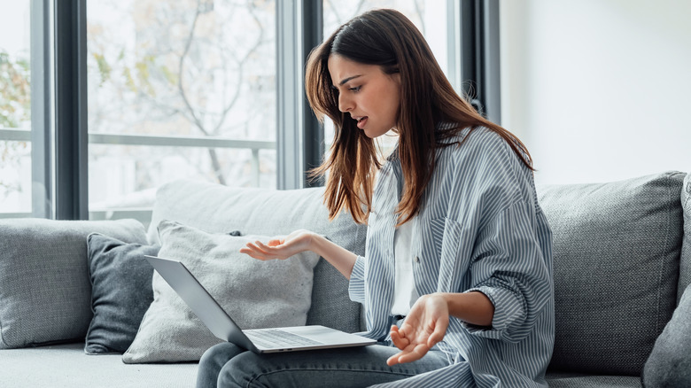 A woman using a laptop and looking exasperated.