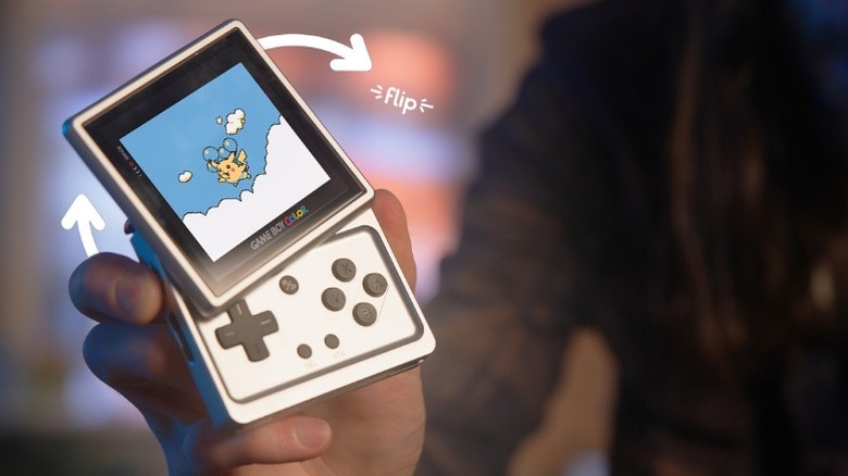 A person holding up the Anbernic RG Rotate, a retro handheld console with a display that flips out.