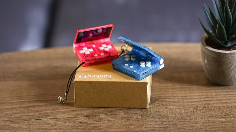 A pair of the Funkey S compact retro gaming consoles in pink and blue sitting on top of the Funkey S box.