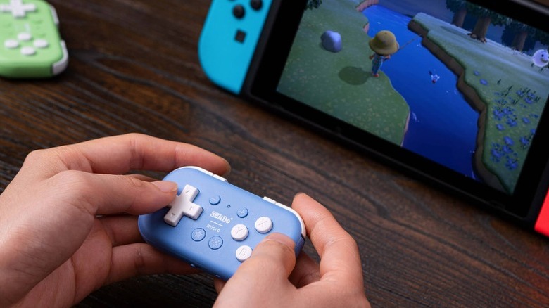 A person playing Animal Crossing on their Nintendo Switch using the 8bitdo Micro Gamepad.