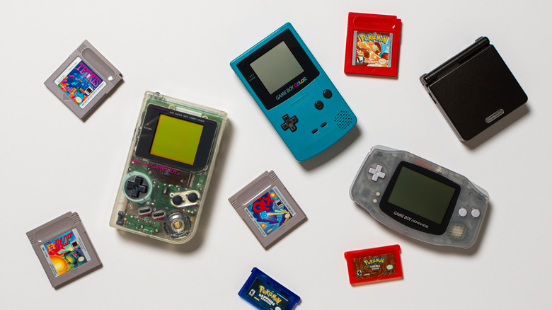 An assortment of Nintendo Game Boys and Nintendo game cartridges against a white background.