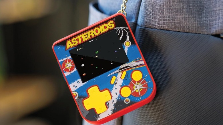 The Super Micro Keychain console with the Asteroids game attached to a backpack by its keychain.