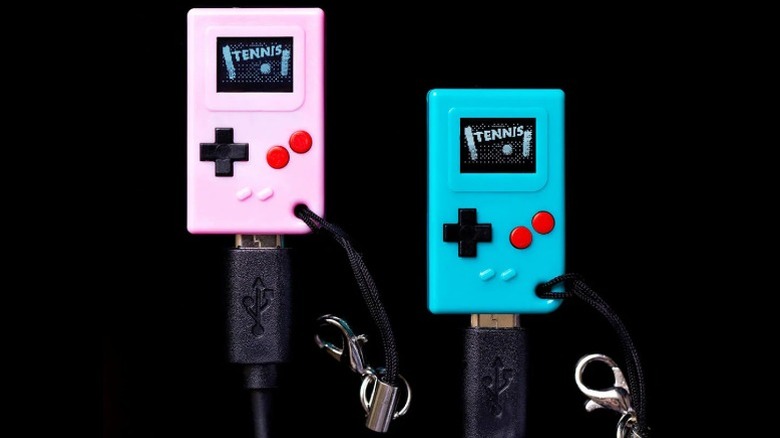 A pair of TinyCircuits Thumby mini consoles in pink and blue with micro-USB cables plugged in at the bottom.