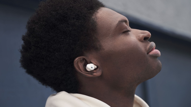 A person wearing Beats earbuds with their eyes closed