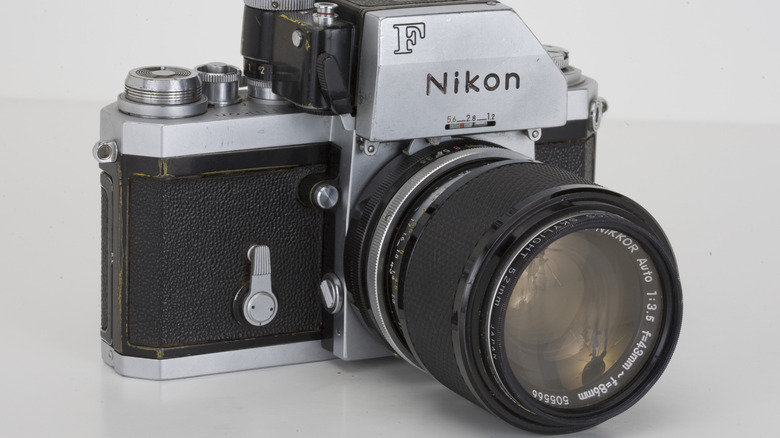 Vintage Nikon F film SLR camera with attached telephoto lens.