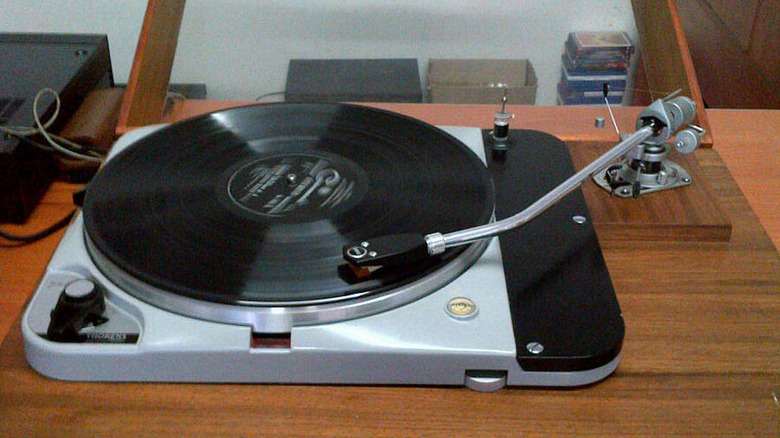 Vintage turntable playing a vinyl record with exposed tonearm.