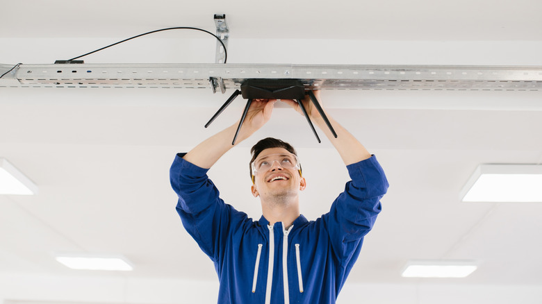 A man installing a router on the ceiling