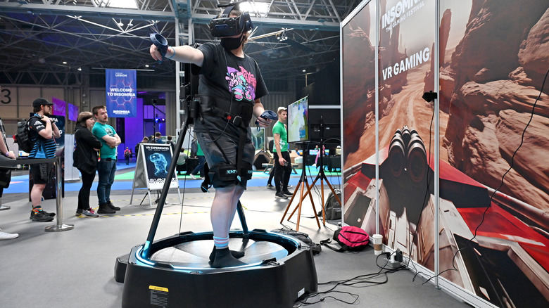 A person using a virtual reality headset and motion-tracking platform to play an immersive VR game at a gaming convention or technology expo.