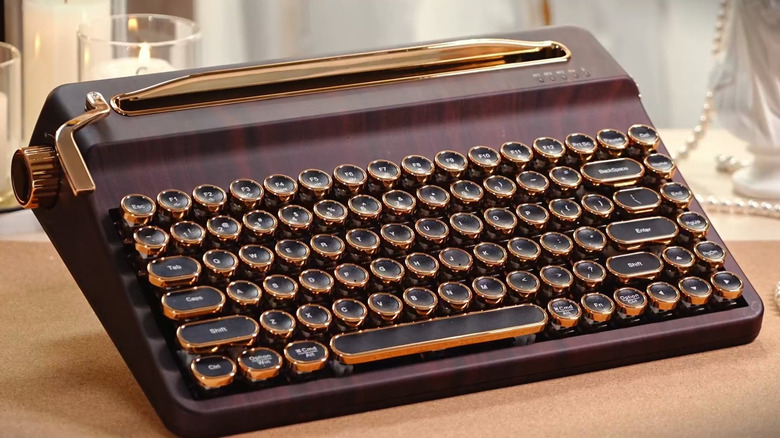 A brown Yunzii QL75 wireless typewriter-style mechanical keyboard with pearls and candles in the background.