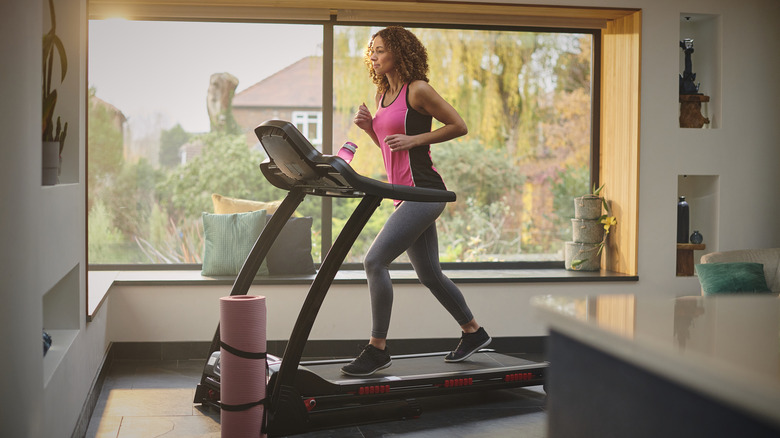 A woman running on a treadmill at home.
