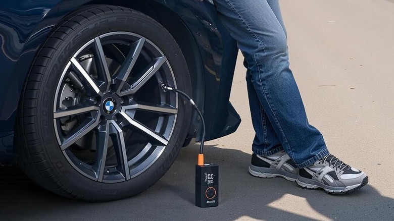The AstroAI L7 portable tire inflator, attached to a car's tire.