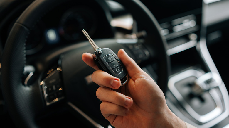 A person holding a car key while inside a vehicle.